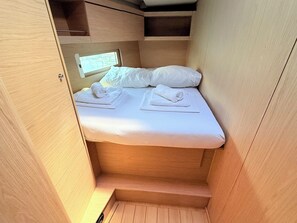 A compact, wooden interior with a bed, two rolled towels, and a window. - Sun-Kissed Sailing Adventure in Zadar, Croatia (Bibinje)