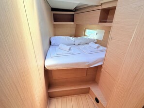 A compact, wooden cabin-style room with a bed, pillows, and neatly folded towels. - Sun-Kissed Sailing Adventure in Zadar, Croatia (Bibinje)
