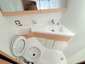 A bathroom with a toilet, sink, mirror, and storage cabinets. - Sun-Kissed Sailing Adventure in Zadar, Croatia (Bibinje)