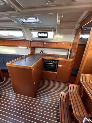 A compact kitchen with a sink, stove, and storage cabinets. - Sun-Kissed Sailing Adventure in Zadar, Croatia (Bibinje)