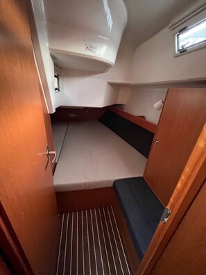 Un espai interior petit amb una banca, una finestra petita i una porta.