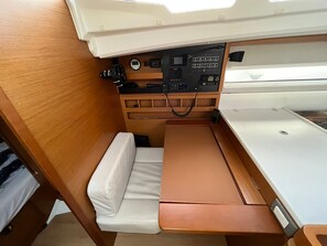 A compact interior with a wooden bench, a small table, and a control panel with various buttons and displays. - Sun-Kissed Sailing Adventure in Zadar, Croatia (Bibinje)