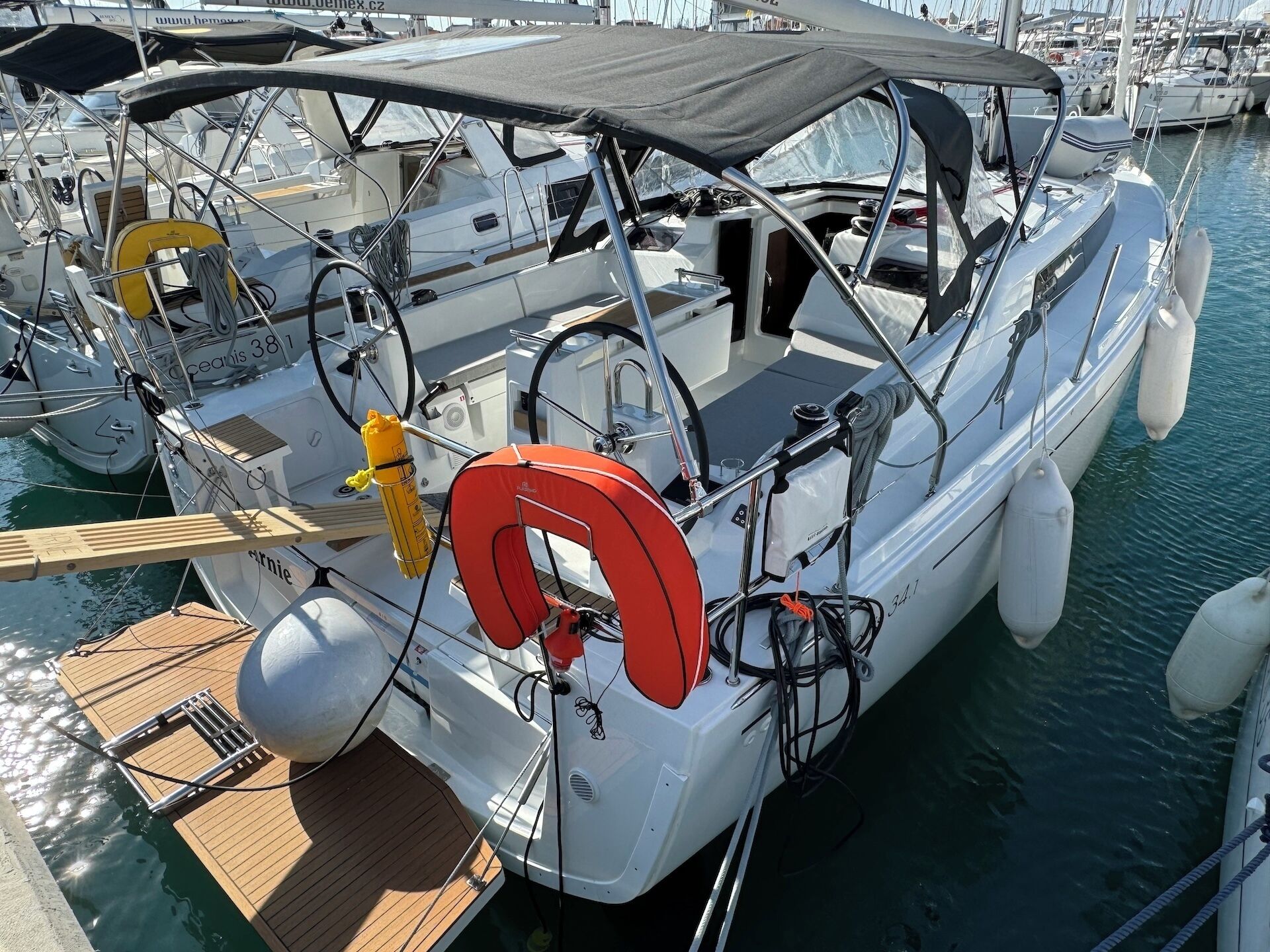A boat docked at a marina with a covered deck, life preserver, and various ropes and equipment.