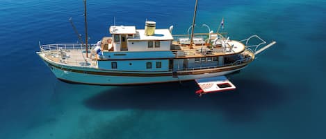 A boat with a cabin, deck chairs, and a flag.