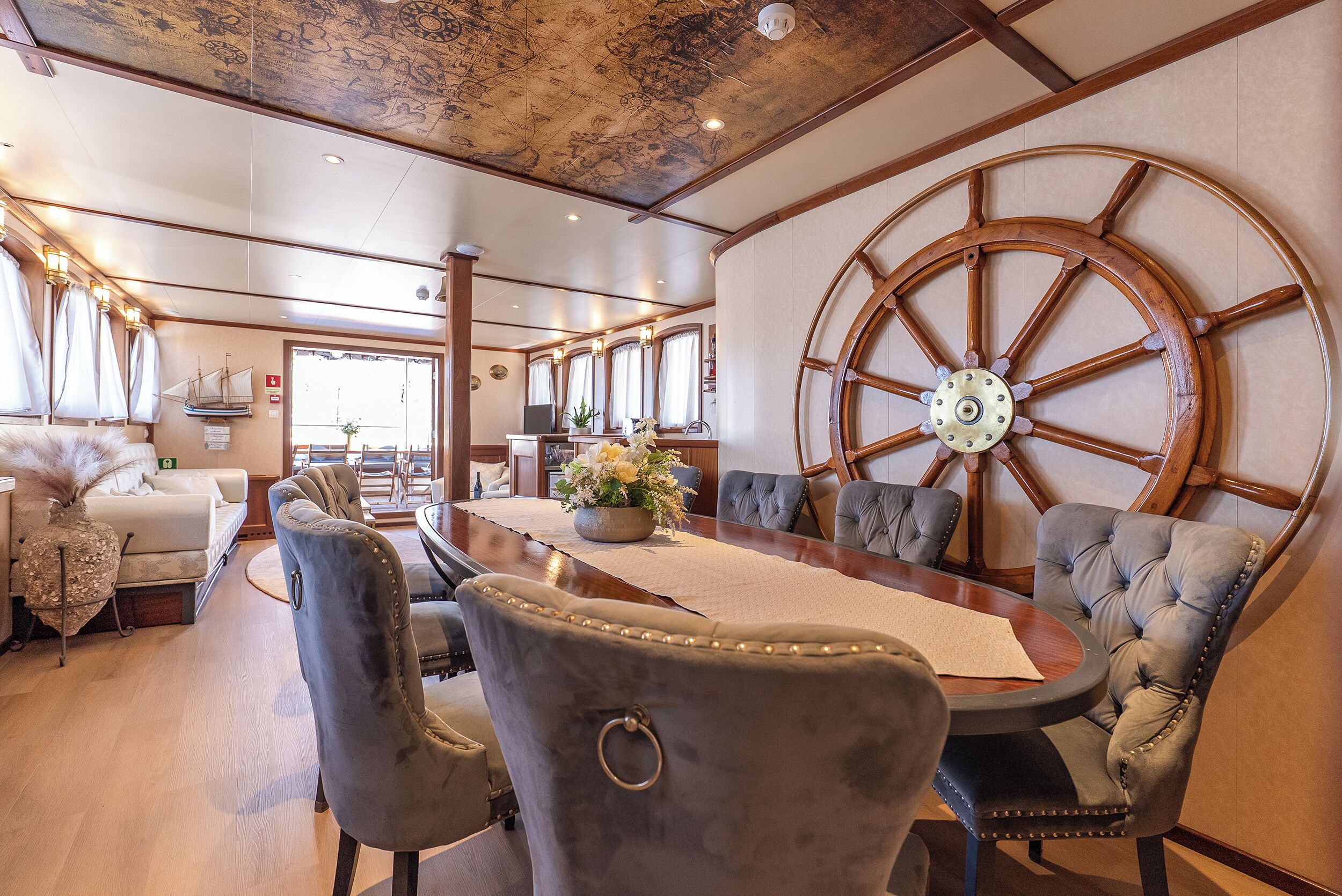 Zona pranzo con una grande ruota di legno, sedie confortevoli e un tavolo con un vaso di fiori.