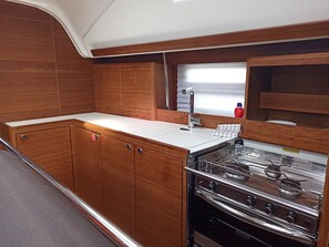 A compact kitchen with wooden cabinets, a stainless steel stove, and a white countertop. - Sun-Kissed Sailing Adventure in Northern Croatia (Punat)