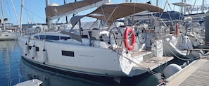 Eine weiße Yacht liegt in einer Marina festgemacht, mit einem Rettungsring und einer sichtbaren Website-URL.