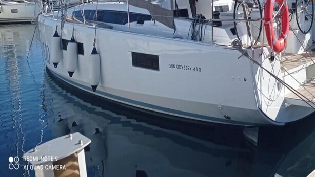 A sailboat docked at a marina with a lifebuoy and a website URL visible.