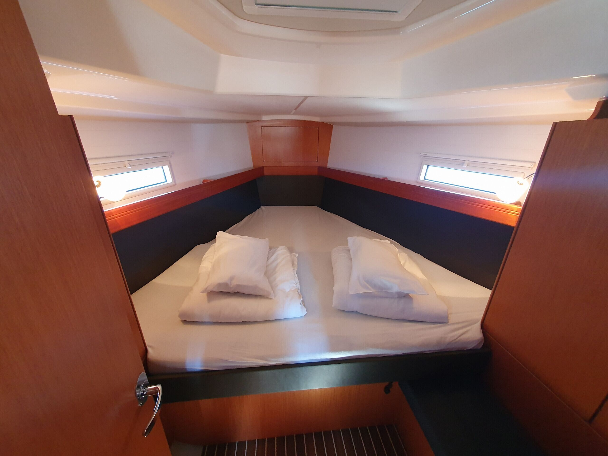 A compact cabin with a single bed, two windows, and a small ventilation panel.
