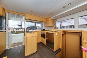 A compact galley with wooden cabinetry, a sink, a stove, and a refrigerator.