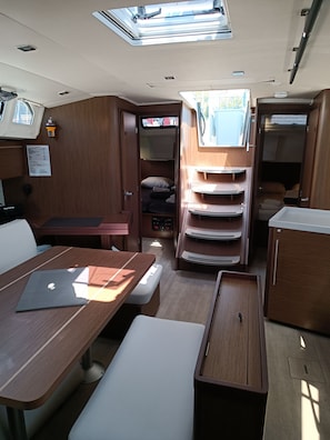 Ein kompaktes Wohnmobil-Interieur mit Essbereich, einer kleinen Küchenzeile und einem Schlafbereich mit Etagenbett.