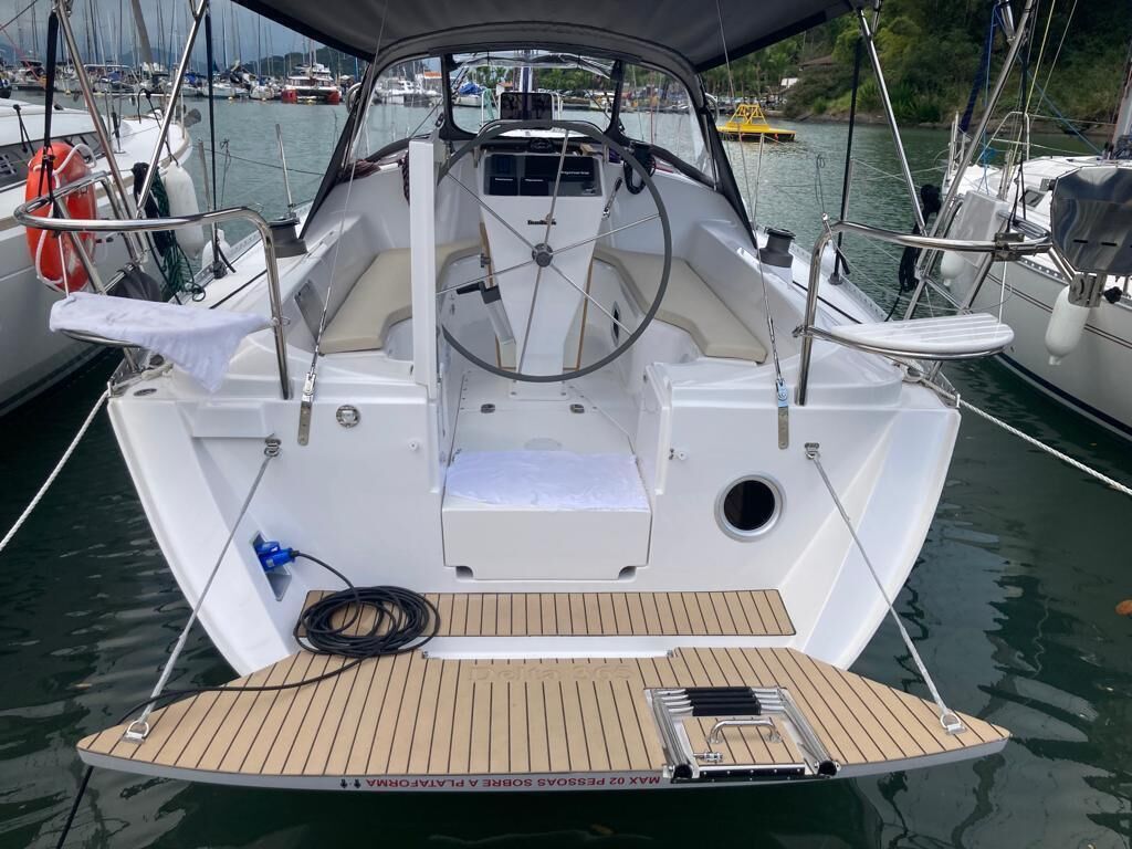 Le pont d’un bateau, avec une roue de barre, un petit espace pour s’asseoir et un gilet de sauvetage.