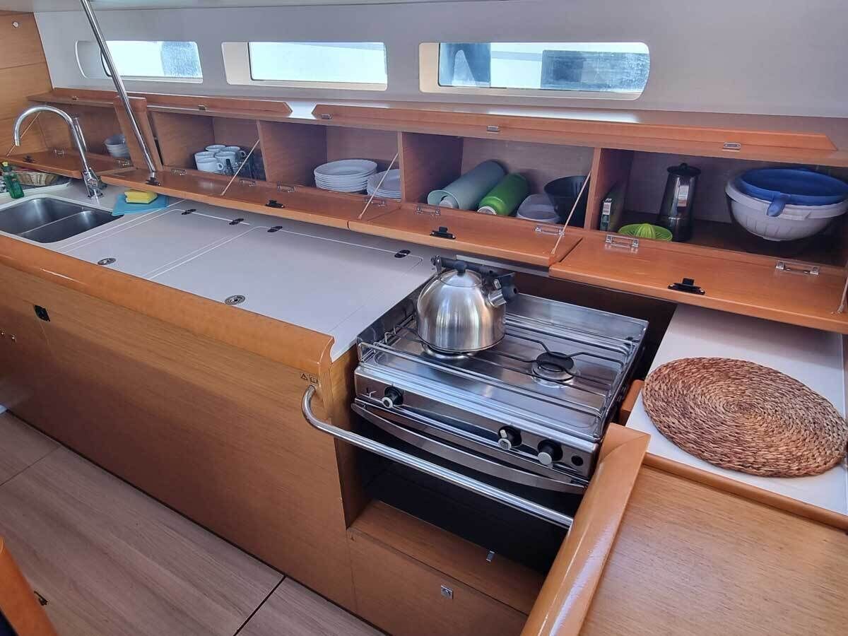 Een kleine keuken met een fornuis, spoelbak en houten kastjes.