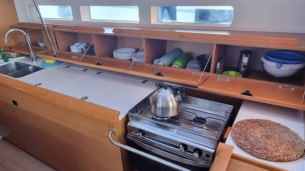 Una cucina compatta con fornello, lavello e pensili in legno.
