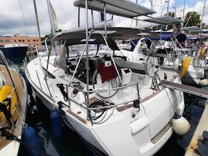 Un velero atracado en un puerto deportivo con una cubierta techada, un cabrestante y un flotador salvavidas.
