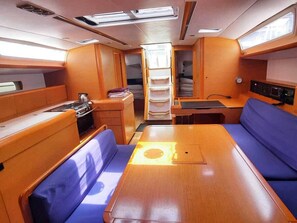 Een compact interieur met een centrale tafel, zitplaatsen aan beide kanten en een klein keukenblok.