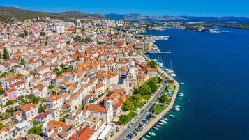 Vista aérea de una ciudad costera con edificios urbanos densos, un puerto deportivo con barcos y una iglesia destacada con cúpula.