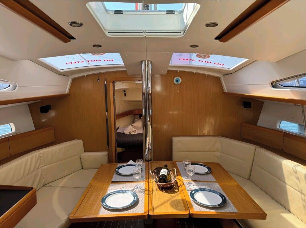 A boat interior with a dining area, cushioned seating, and a central aisle.