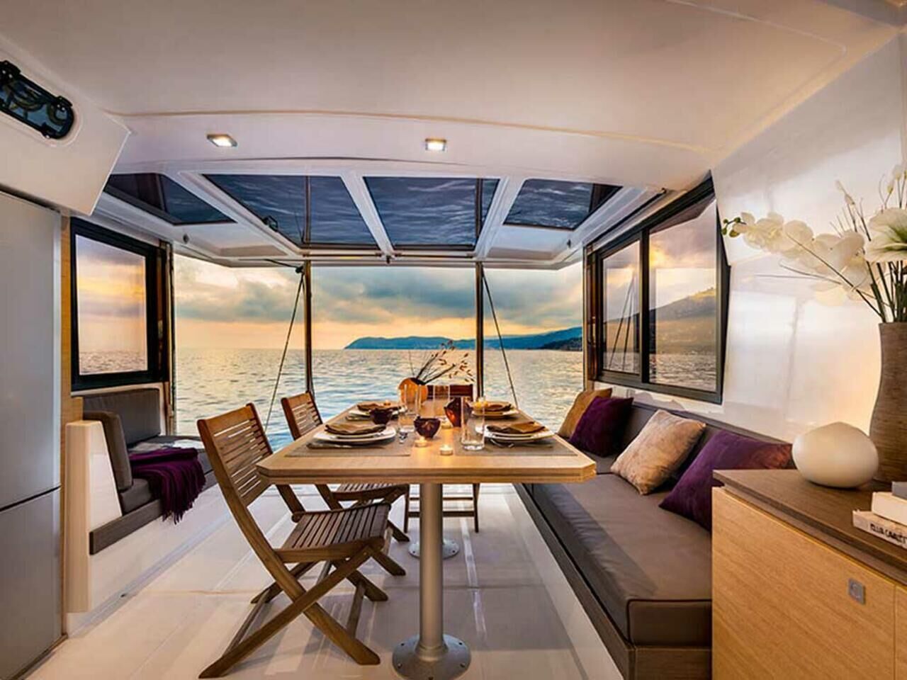 Un comedor con una mesa dispuesta para dos personas, un sofá y vista al mar.