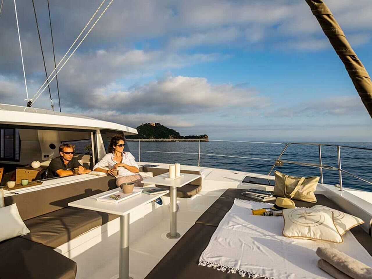 Een jacht met een dekgedeelte met een bank, een tafel en uitzicht op zee.