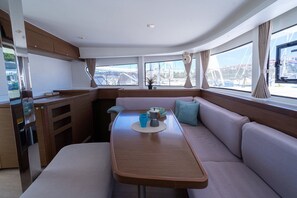 Een kleine kombuis met eettafel, zithoek en grote ramen met uitzicht op de jachthaven.
