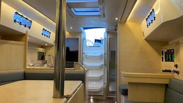 A boat interior with seating areas, a central aisle, and overhead windows.