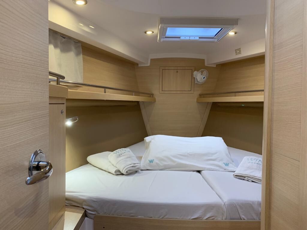 A compact cabin with bunk beds, a skylight, and a small fan.