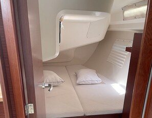 Une petite pièce avec un lit superposé, une petite fenêtre avec des stores et une porte.