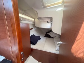 Een compacte cabine met een stapelbed, een klein wastafeltje en een opbergvak.