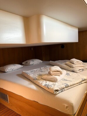 A bunk bed with a headboard, a bed with a patterned duvet, and several pillows. - Sun-kissed Sailing Adventure in Split-Dalmatia, Croatia (Seget Donji)