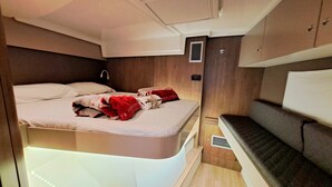 A compact, well-lit interior with a bed, a bench, and a small table. - Sun-Kissed Sailing Adventure in the Majestic Islas Baleares (Sant Antoni de Portmany)