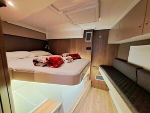 Ein kompakter, gut beleuchteter Innenraum mit einem Bett, einer Bank und einem kleinen Tisch.