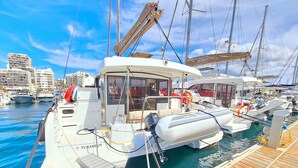 A marina with boats docked, a wooden deck, and a cityscape in the background. - Sun-Kissed Sailing Adventure in the Majestic Islas Baleares (Sant Antoni de Portmany)