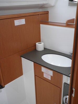 A small bathroom with a wooden cabinet, a white sink, and a toilet. - Sun-Kissed Sailing Adventure in Zadar, Croatia (Bibinje)