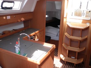 A compact galley with a sink, storage cabinets, and a small bed. - Sun-Kissed Sailing Adventure in Zadar, Croatia (Bibinje)