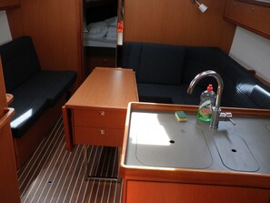 A compact kitchenette with a sink, a small storage drawer, a bench, and a couch. - Sun-Kissed Sailing Adventure in Zadar, Croatia (Bibinje)