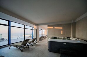 A modern spa area with a hot tub, lounge chairs, and large windows offering a view.