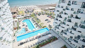A hotel with a swimming pool, beach view, and multiple balconies.