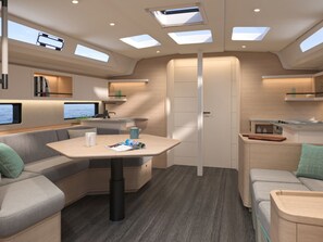 A modern RV interior with a dining area, seating, a kitchen, and a TV.