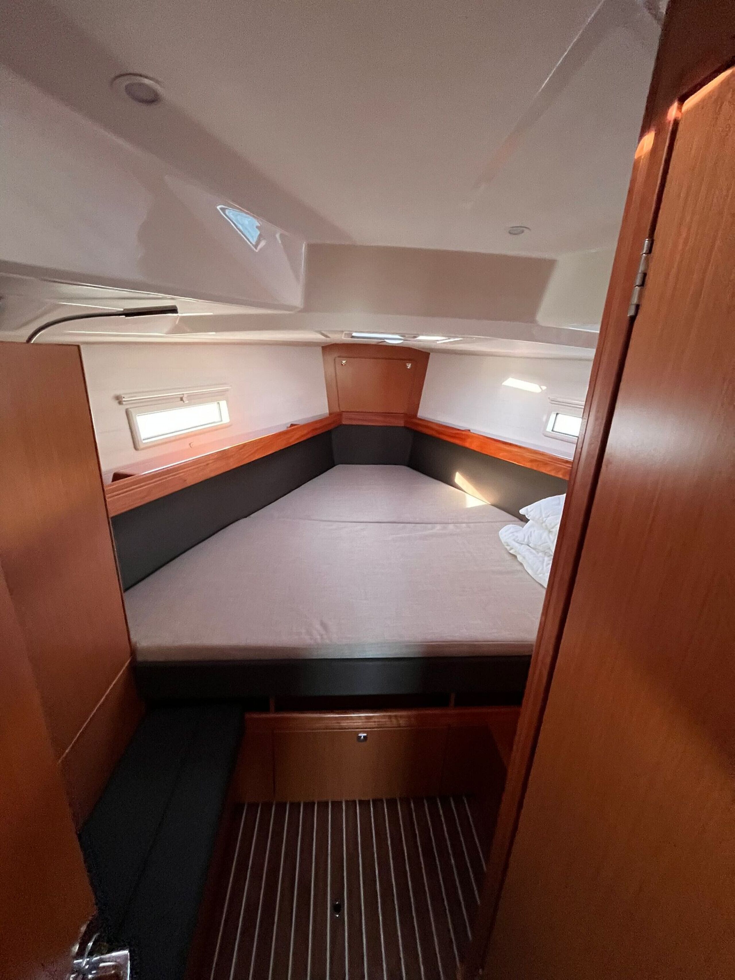 A compact cabin with a single bed, a small window, and a built-in storage compartment.