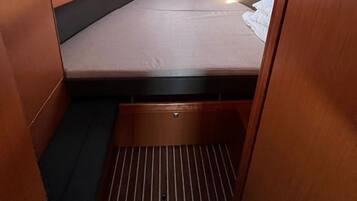 A compact cabin with a single bed, a small window, and a built-in storage compartment.