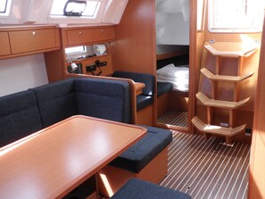 Ein kompaktes Interieur mit Sitzbank, einem kleinen Tisch, einem Bett und einem Ablagefach.