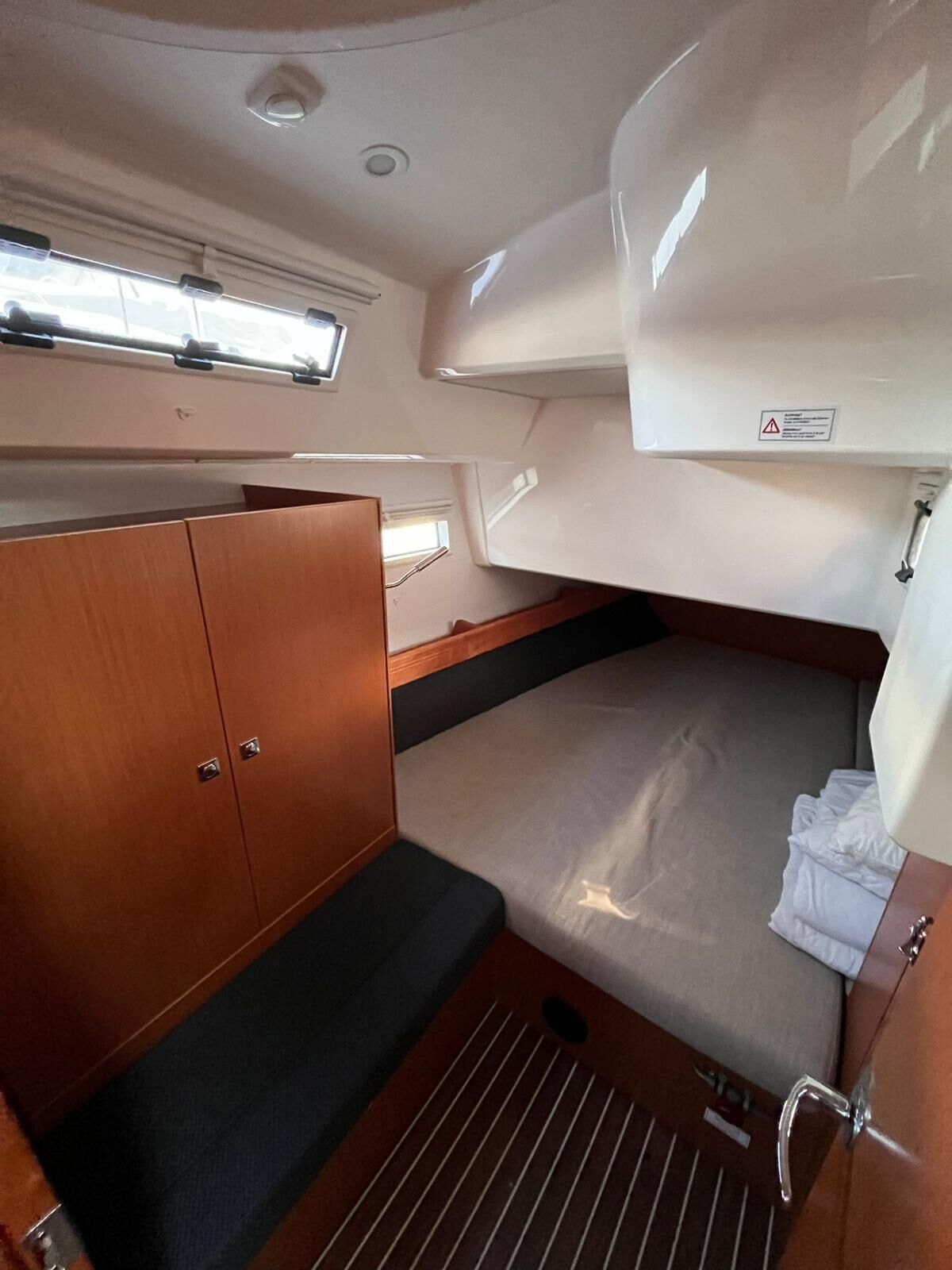 A compact interior with a bunk bed, wooden wardrobe, and a small window.