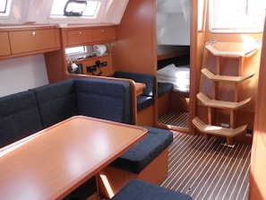 A compact interior with a bench seating area, a small table, a bed, and a storage shelf. - Sun-Kissed Sailing Adventure in Zadar, Croatia (Bibinje)