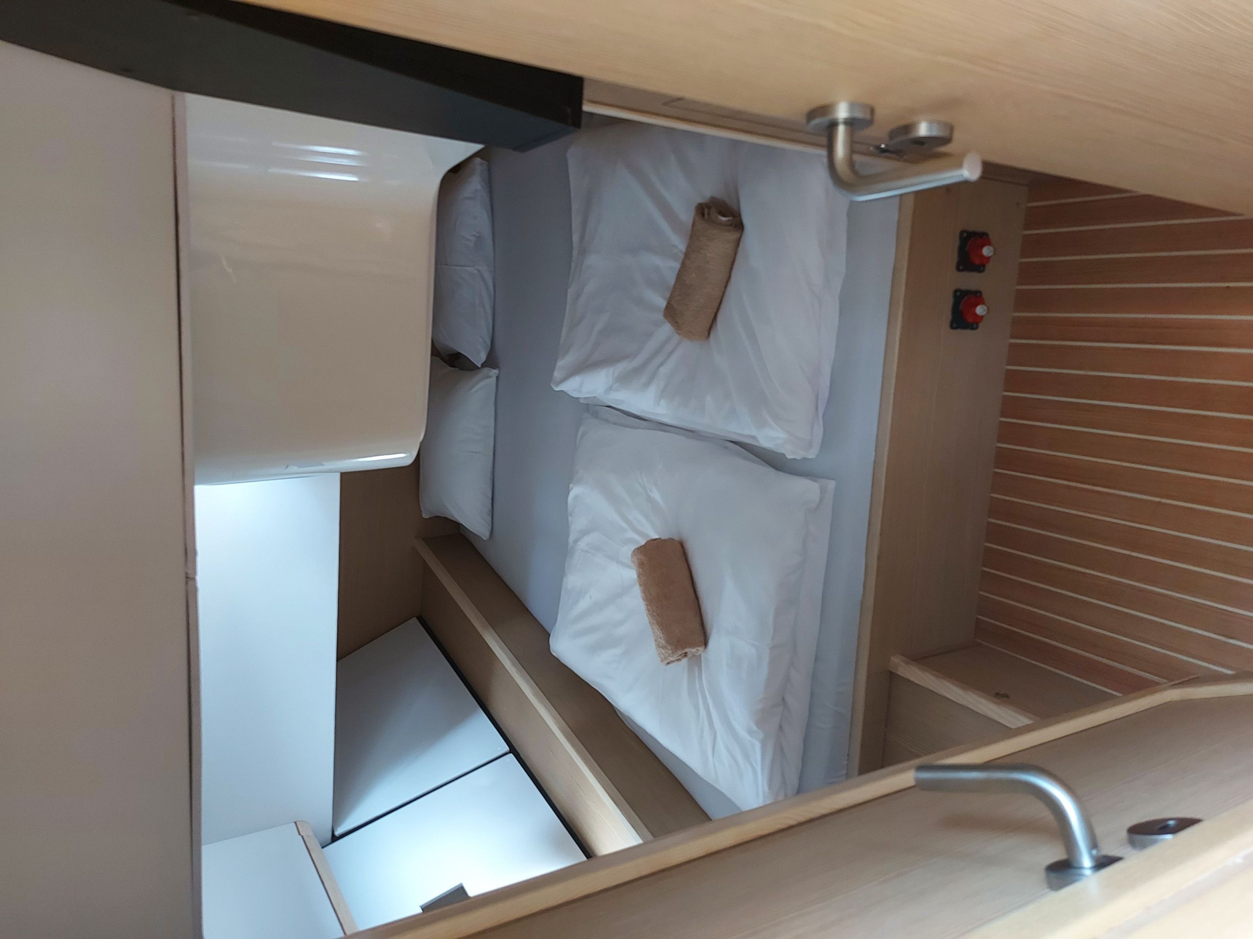 A compact, enclosed sleeping area with a bunk bed, a small shelf, and a control panel with buttons.