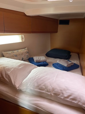 Une chambre à coucher de taille modeste, équipée de deux lits, chacun avec des oreillers et des serviettes pliées.
