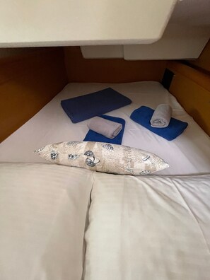 Ein Bett mit Kissen, zwei zusammengerollten Handtüchern und einer gefalteten Decke.