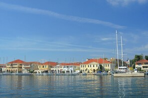 A marina with multiple boats docked, a large sailboat, and buildings with red roofs. - Sun-kissed Sailing Adventure in the Ionian Islands (Preveza)