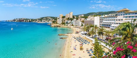 Un hotel costero con acceso directo a la playa, varios pisos y vistas al mar.