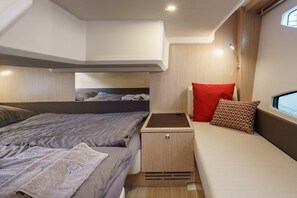 Un interior compacto y bien iluminado con una cama, un pequeño rincón de descanso y una ventana.
